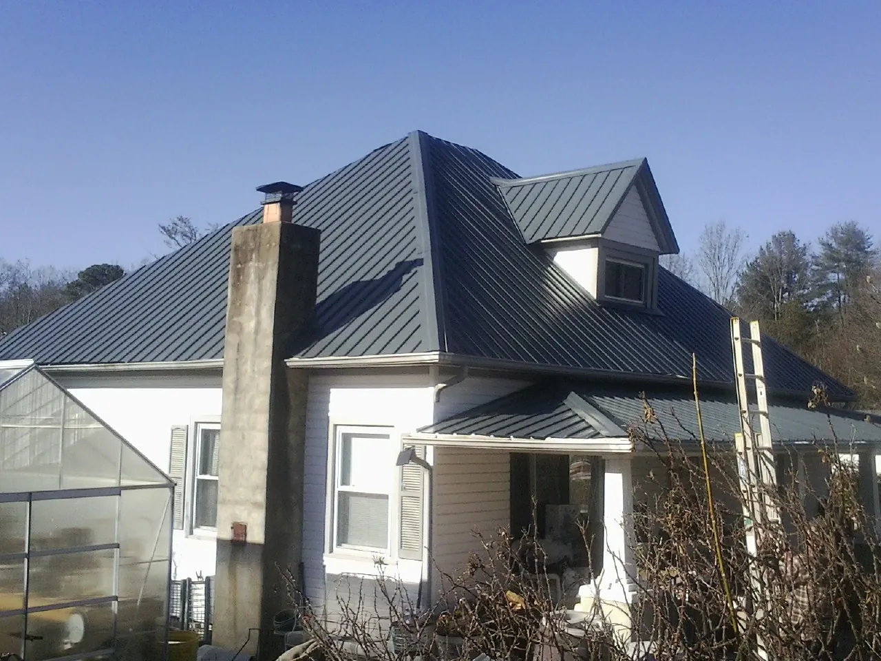 Dark blue standing seam metal roof on a white farmhouse with dormer — Slate & Tile Roof Repair by Roofing Brothers in Port Reading