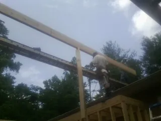 Carpenter setting a ridge beam over a new addition frame — Ice Dam Removal by Roofing Brothers in Port Reading