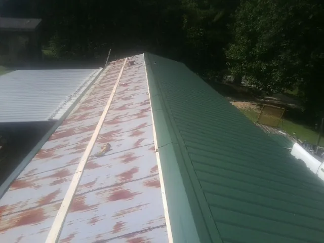 Old rusted panels beside newly installed green metal roofing — Wind Damage Roof Repair by Roofing Brothers in Port Reading