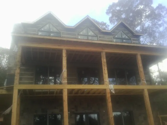 Dormers and porch framing on a large log home under construction — Roof Coating work by our crew in Port Reading