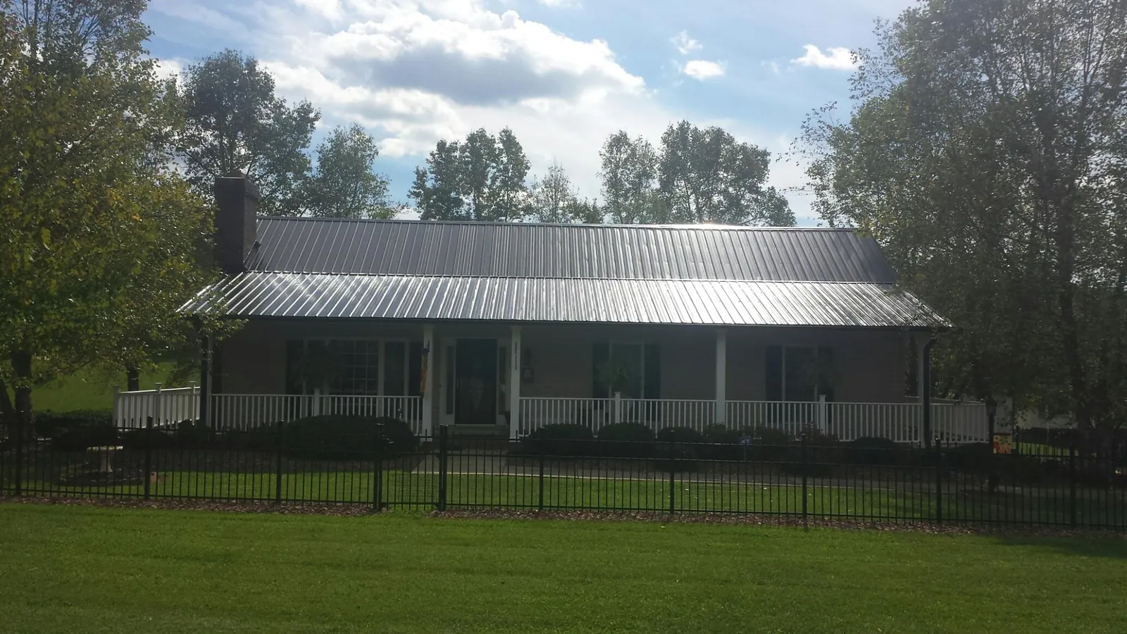 Gray metal roof on a brick ranch with a full width front porch — Gutter Guard Installation work by our crew in Port Reading