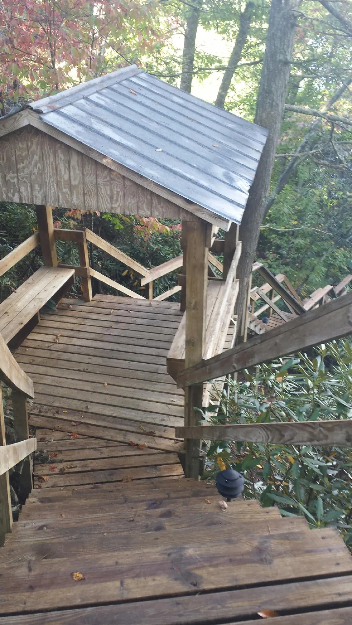 Metal roofed shelter over wooden steps on a wooded walkway — Skylight Repair & Installation work by our crew in Port Reading