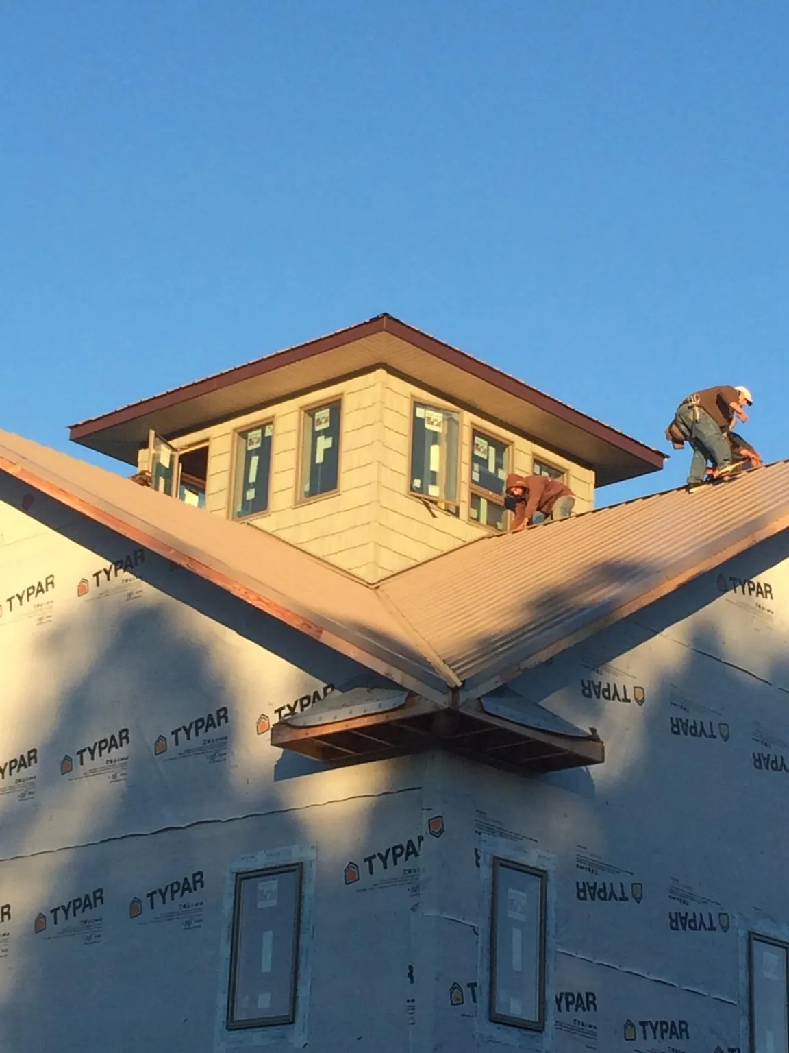 Roofers working around a rooftop cupola on a new metal roof at sunset — Roof Waterproofing in Port Reading by Roofing Brothers